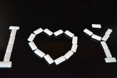 Yiyecek, kişisel bakım ürünleri, ürün, sakız, beyaz çiğneme yastıkları, siyah parlak bir arka planda sıralanmış sakız..