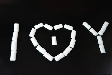 Yiyecek, kişisel bakım ürünleri, ürün, sakız, beyaz çiğneme yastıkları, siyah parlak bir arka planda sıralanmış sakız..