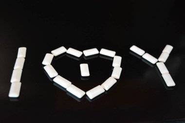 Yiyecek, kişisel bakım ürünleri, ürün, sakız, beyaz çiğneme yastıkları, siyah parlak bir arka planda sıralanmış sakız..