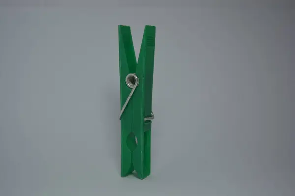 Ordinary things that are used in everyday life. Beautiful green plastic clothespins placed on white background.
