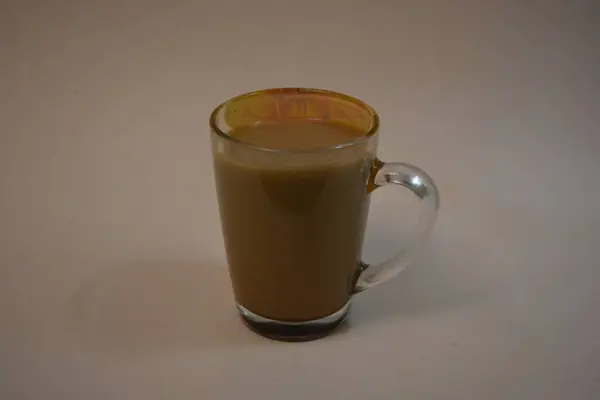 Large glass mug of coffee with milk placed on a black glossy background.