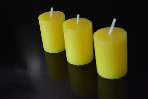 Home furnishings, yellow bright candles placed on black glossy background.