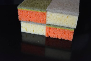 Evde sıkça kullanılan şeyler. Bulaşık yıkamak için renkli havlular parlak siyah bir arka planda düzenlenir..