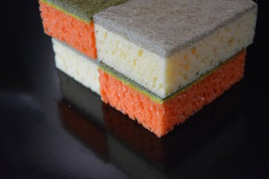 Evde sıkça kullanılan şeyler. Bulaşık yıkamak için renkli havlular parlak siyah bir arka planda düzenlenir..