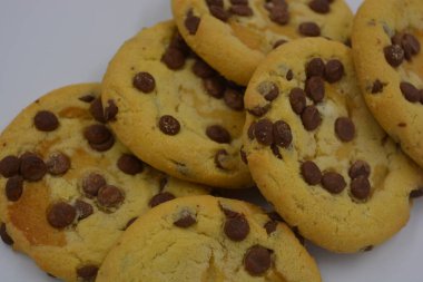 Tatlı, lezzetli, büyük kurabiyeler beyaz arka planda küçük süt parçacıkları olan çikolatalar..