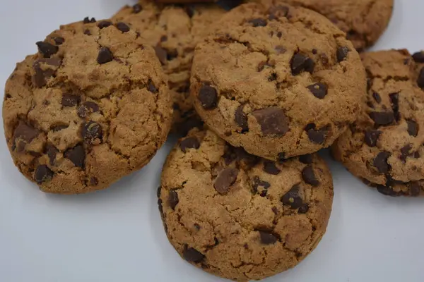 Sweets, delicious chocolate chip cookies with large chunks of milk and dark chocolate arranged on a white background.