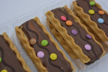 Tatlılar, lezzetli, ilginç tatlılar, karamelli kurabiyeler, sütlü çikolata ve beyaz arka planda küçük renkli şekerler..