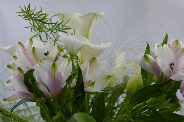 A beautiful, festive and bright bouquet, a composition of white calla lilies, purple white orchids, flowers with green leaves, branches.