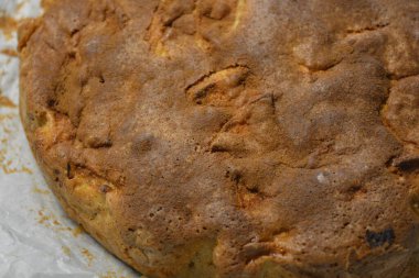 Kuru üzümlü ev yapımı kek ve fırın kağıdı. Siyah arka planda kremalı elmalı turta, yakın plan. Fin mutfağı, ev yapımı kekler, Charlotte elmalı lezzetli turta..