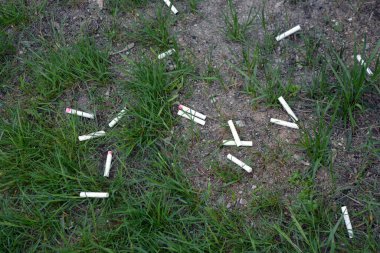 Yaşam tarzı, sağlığı öldüren sigara. Yere atılmış bir sürü yarı tütsülenmiş sigara. Çok sayıda beyaz sigara izmariti ve kırmızı ruj..