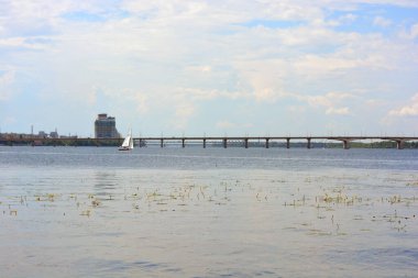 Geniş, uzun mavi Dnipro Nehri 'nin güzel manzarası. Manzaralar, yeşil ağaçlı gri tuğla seti, yeni inşaat alanları ve Dnipro şehrindeki köprü..