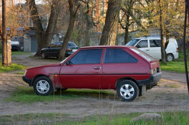 Ukrayna yapımı yeni bir araba Ukrayna 'daki bir evin avlusunda duruyor. Koyu kırmızı, kirazlı Tavria arabası koyu renk araba camları ve gümüş lastikleri var..