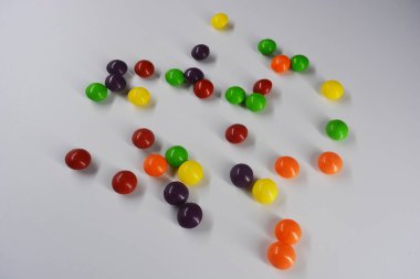Güzel, parlak çiğneme ve şeker renkli diş mineleriyle kaplı çikolata şekerleri beyaz plastik bir arka planda yer almaktadır..