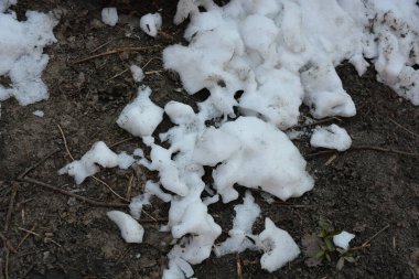 Kış, parlak manzara. Kara toprak, erimiş beyaz kar ve buzla kaplı bir sebze bahçesi..