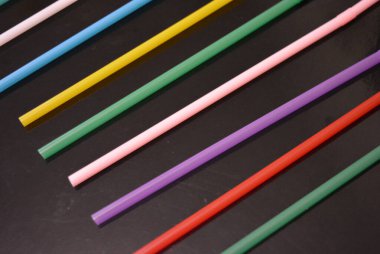 Alışılmadık geçmişleri, sanat eserleri. Birçok kırmızı, beyaz, mavi, yeşil, mor, pembe, sarı plastik pipetler siyah parlak arka planda yer almaktadır..