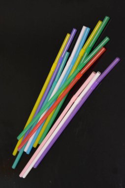 Alışılmadık geçmişleri, sanat eserleri. Birçok kırmızı, beyaz, mavi, yeşil, mor, pembe, sarı plastik pipetler siyah parlak arka planda yer almaktadır..