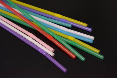 Alışılmadık geçmişleri, sanat eserleri. Birçok kırmızı, beyaz, mavi, yeşil, mor, pembe, sarı plastik pipetler siyah parlak arka planda yer almaktadır..