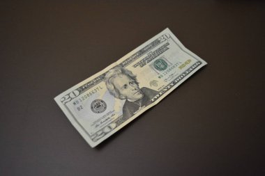 Her gün kullanılan eşyalar ve eşyalar yirmi dolardır. Ekonomi, finans, finansal okur yazarlık. Kağıt olarak 20 dolar tutarında Amerikan doları kahverengi bir arka planda düzenlenmiştir..