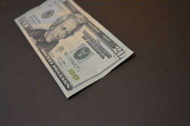 Her gün kullanılan eşyalar ve eşyalar yirmi dolardır. Ekonomi, finans, finansal okur yazarlık. Kağıt olarak 20 dolar tutarında Amerikan doları kahverengi bir arka planda düzenlenmiştir..