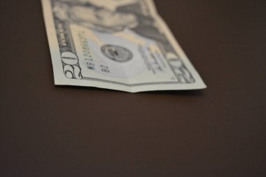 Her gün kullanılan eşyalar ve eşyalar yirmi dolardır. Ekonomi, finans, finansal okur yazarlık. Kağıt olarak 20 dolar tutarında Amerikan doları kahverengi bir arka planda düzenlenmiştir..