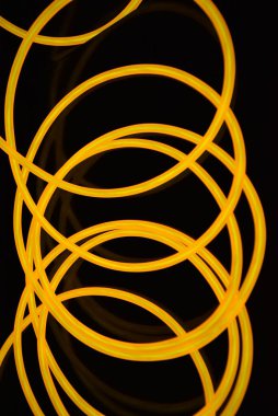 Güzel, kalın, turuncu kablolar kaotik bir şekilde siyah plastik bir arka planda yer alıyor ve bükülüyor. Elektroaydınlatma kablosu, neon tüpleri, plastiğin içindeki ışık, kablolar, ışıklandırma, yaratıcılık.