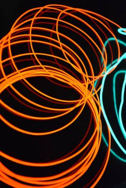 Sıra dışı parlayan mavi ve kırmızı iplik, bükülmüş tel, yapısal ve kıvrımlı kablo. Neon elektroaydınlatma kablosu, kablo, plastik neon ışıkla eşit derecede parlar..