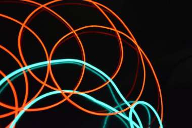 Sıra dışı parlayan mavi ve kırmızı iplik, bükülmüş tel, yapısal ve kıvrımlı kablo. Neon elektroaydınlatma kablosu, kablo, plastik neon ışıkla eşit derecede parlar..