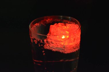 Güzel ve parlak kırmızı parlayan buz küpü bir bardak şampanya bardağında süzülür. Buz kübü şeklinde plastik şeyler. Dahili diyot. Kokteyli aydınlatır, köpüklü içecek..
