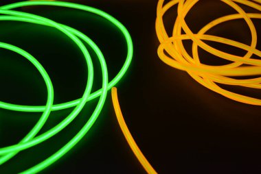 Parlak parlak kablolar, yeşil, limon, kireç, turuncu, turuncu ışık çizgileri. Neon kaotik çizgiler spiraller, daireler ve kıvrımlar halinde siyah bir arkaplanda dizilir..