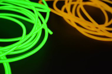 Parlak parlak kablolar, yeşil, limon, kireç, turuncu, turuncu ışık çizgileri. Neon kaotik çizgiler spiraller, daireler ve kıvrımlar halinde siyah bir arkaplanda dizilir..