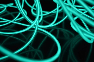 Parlak parlak elektroaydınlatma kabloları, açık yeşil, yeşil, mavi, gök mavisi, turkuaz kalın ışık çizgileri. Neon kaotik çizgiler spiraller, daireler ve kıvrımlar halinde siyah bir arkaplanda dizilir..