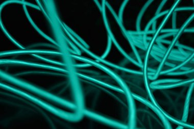 Parlak parlak elektroaydınlatma kabloları, açık yeşil, yeşil, mavi, gök mavisi, turkuaz kalın ışık çizgileri. Neon kaotik çizgiler spiraller, daireler ve kıvrımlar halinde siyah bir arkaplanda dizilir..