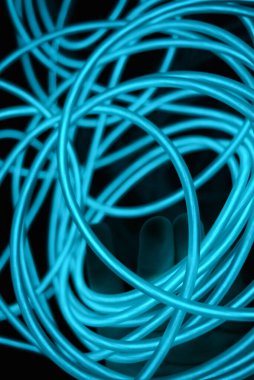 Parlak parlak elektroaydınlatma kabloları, açık yeşil, yeşil, mavi, gök mavisi, turkuaz kalın ışık çizgileri. Neon kaotik çizgiler spiraller, daireler ve kıvrımlar halinde siyah bir arkaplanda dizilir..