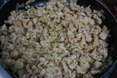 Yemek hazırlama, kızarmış beyaz soğanlı küçük tavuk parçaları, siyah metal kızartma tavasında pişirilmiş..