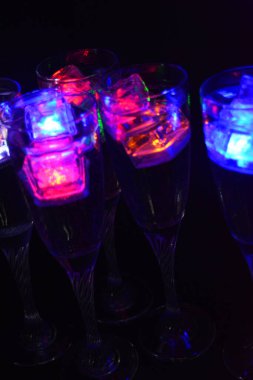 Parlayan şeylerin olduğu bir parti. Renkli bardaklar, köpüklü şampanya bardakları, karbonatlı tatlı su, parlayan buz küpleri, donmuş buz. Kırmızı, mavi, yeşil, sarı, beyaz ışık içecekleri içinde yüzen LED 'li plastik buz küpleri.