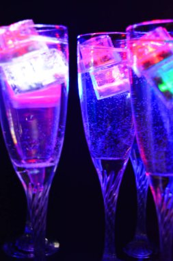Parlayan şeylerin olduğu bir parti. Renkli bardaklar, köpüklü şampanya bardakları, karbonatlı tatlı su, parlayan buz küpleri, donmuş buz. Kırmızı, mavi, yeşil, sarı, beyaz ışık içecekleri içinde yüzen LED 'li plastik buz küpleri.