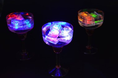 Parlayan şeylerin olduğu bir parti. Renkli bardaklar, köpüklü şampanya bardakları, karbonatlı tatlı su, parlayan buz küpleri, donmuş buz. Kırmızı, mavi, yeşil, sarı, beyaz ışık içecekleri içinde yüzen LED 'li plastik buz küpleri.