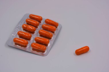 İlaç, tıbbi hazırlıklar, haplar. İçinde ilaç bulunan turuncu kapsüller metal bir kaydırağın içinde..