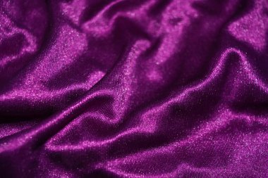 Kumaşlar, giysiler, nesneler, koyu mor arka planlar. Güzel parlak kadifemsi mor kumaş. İlginç bir parıltı, yansıması var..