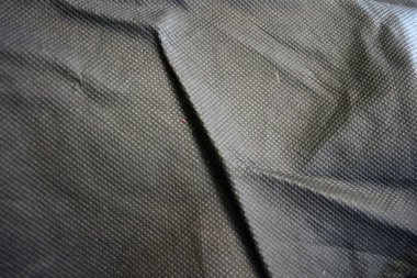 Paketleme malzemeleri, siyah sentetik kumaş iyi bir açıda duruyor. Küçük kareler şeklinde alışılmadık gri, açık siyah bir arkaplan..