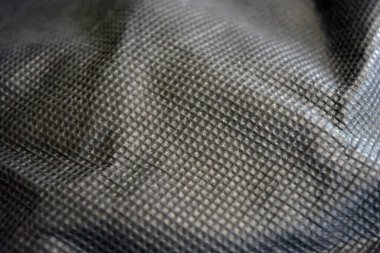 Paketleme malzemeleri, siyah sentetik kumaş iyi bir açıda duruyor. Küçük kareler şeklinde alışılmadık gri, açık siyah bir arkaplan..