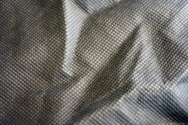 Paketleme malzemeleri, siyah sentetik kumaş iyi bir açıda duruyor. Küçük kareler şeklinde alışılmadık gri, açık siyah bir arkaplan..