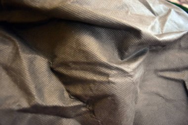 Paketleme malzemeleri, siyah sentetik kumaş iyi bir açıda duruyor. Küçük kareler şeklinde alışılmadık gri, açık siyah bir arkaplan..