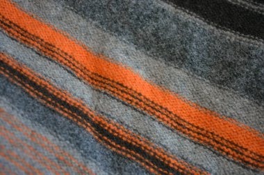 Eşyalar, nesneler, doğal kumaştan yapılmış giysiler. Güzel bir erkek süveteri turuncu, gri, koyu gri, siyah çizgili, doğal yün ipliğinden örülmüş..