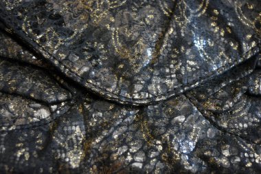 Altın kaplamalı siyah kumaş arkaplan, yansıtıcı plastik pullu altın çiçek desenleri.