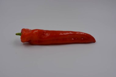 Sağlık, sağlıklı yiyecekler, sebzeler, sağlıklı yiyecekler. Yeşil kuyruklu uzun kırmızı bir dolma biber beyaz bir arka planda yer alır..