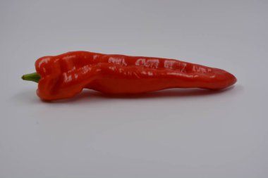 Sağlık, sağlıklı yiyecekler, sebzeler, sağlıklı yiyecekler. Yeşil kuyruklu uzun kırmızı bir dolma biber beyaz bir arka planda yer alır..