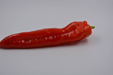 Sağlık, sağlıklı yiyecekler, sebzeler, sağlıklı yiyecekler. Yeşil kuyruklu uzun kırmızı bir dolma biber beyaz bir arka planda yer alır..