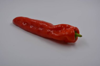 Sağlık, sağlıklı yiyecekler, sebzeler, sağlıklı yiyecekler. Yeşil kuyruklu uzun kırmızı bir dolma biber beyaz bir arka planda yer alır..