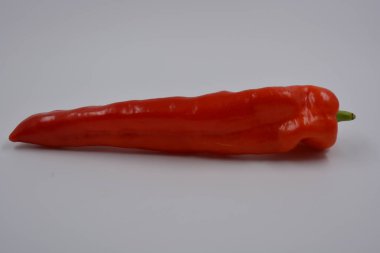 Sağlık, sağlıklı yiyecekler, sebzeler, sağlıklı yiyecekler. Yeşil kuyruklu uzun kırmızı bir dolma biber beyaz bir arka planda yer alır..